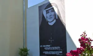 Plakat z portretem św. Faustyny na ścianie budynku, z napisem "ST. FAUSTINA".