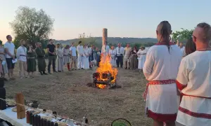 Grupa ludzi w strojach ludowych stoi wokół ogniska podczas obrzędu.